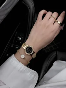 Détail d'une montre à quartz dorée et d'un ensemble de bijoux assortis portés au poignet