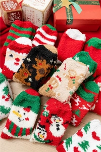 Detailed pile of fuzzy Christmas coral fleece socks with festive patterns on wood background