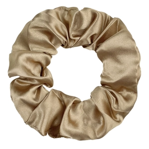Detailed view of large champagne gold satin silk scrunchie with smooth glossy texture