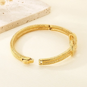 Golden hinged knot bangle with dual-row spiral texture on a minimalist natural background