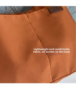 Detail of caramel canvas tote showing fabric texture, fine stitching, and fashion logo patch