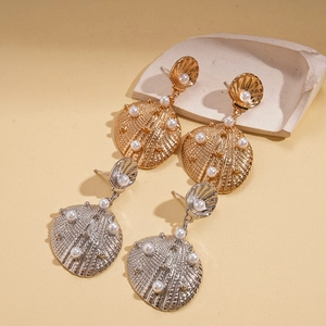 Chic shell-shaped earrings with pearls in gold and silver finish on a textured background