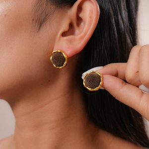 Detail view of round vintage flocked stud earrings with gold trim worn by a model