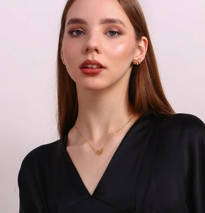 Detailed view of model wearing a gold bow pendant necklace and matching stud earrings