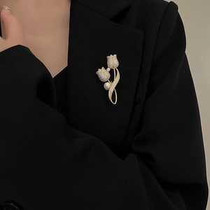 Elegant gold tulip brooch with pearls and diamonds worn on a formal black suit jacket