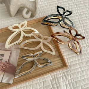Elegant butterfly hair claws in five colors on a wooden tray for women's styling