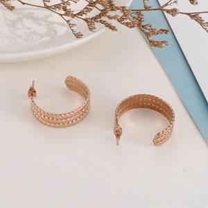 Close-up of rose gold C-shaped earrings with twisted wheat rope texture on white paper