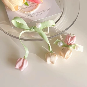 Detailed shot of tulip hair clip with satin ribbons and pearls on glass tray