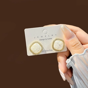Detailed close-up of gold square stud earrings with pearl inlay and 925 silver post