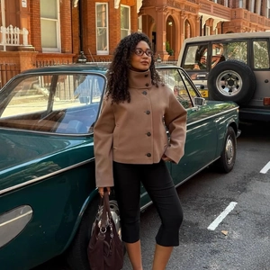 Fashionable brown short wool coat with stand collar and dark buttons in urban street setting