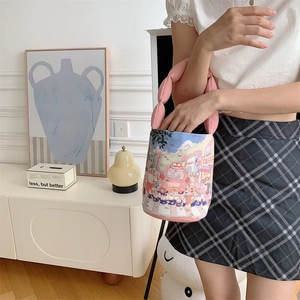 Detail of pink canvas bucket bag featuring cute cartoon street scene and padded handle
