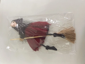 Close-up of Halloween witch doll in red mesh skirt and headscarf in plastic packaging
