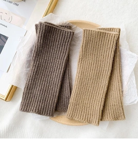 Detail of warm rib-knit fingerless gloves in coffee and khaki on elegant props