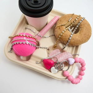 Flat lay of pink beaded bracelets and heart pendant keychains with coffee and bagels