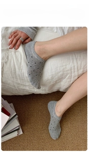 Detailed view of grey low-cut invisible socks with black polka dots on a model in a home setting