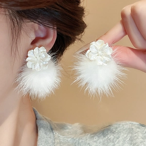 Gros plan de boucles d'oreilles fleur blanche avec pompon en fourrure douce