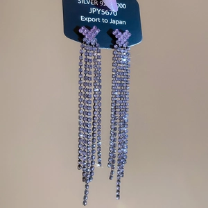 Macro detail of Silver 925 earrings with purple rhinestone tassels and bow design