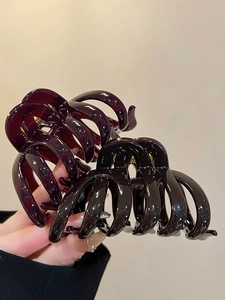 Close-up of large acrylic pumpkin stripe claw clips in burgundy and black with glossy finish
