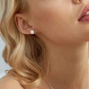 Detail view of round white opal stud earring with gold-plated sterling silver setting