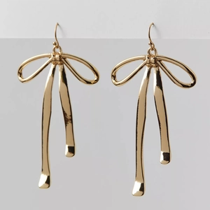 Macro detail of elegant gold ribbon bow earrings with a polished mirror finish