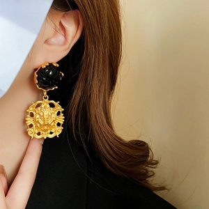 Detail showing vintage lion head gold earring with black flower stud on model