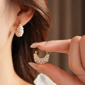 Close-up of French court style gold earring with inset white pearls and rhinestones