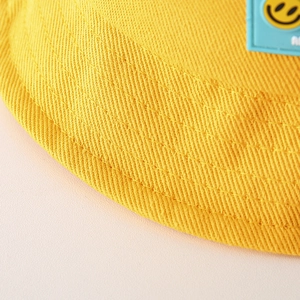 Primo piano macro del cappello alla pescatora giallo per bambini con toppa sorridente