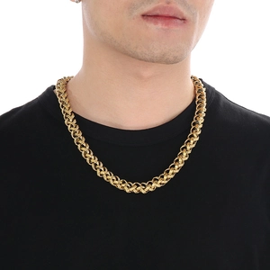 Close-up of a chunky golden woven chain necklace worn by a male model on a black t-shirt