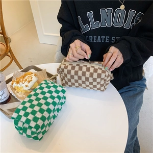 Knitted checkerboard cosmetic bags in green and brown with zipper closure on a cafe table