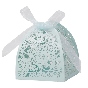 Detail of light blue laser-cut wedding candy box with elegant floral patterns and white ribbon