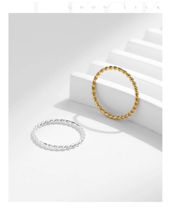 Detailed view of silver and gold twisted rope rings on a white geometric platform