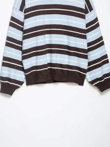 Detail of ribbed cuffs and hem on retro striped knit sweater in brown and blue