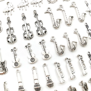 Macro shot of silver vintage musical instrument charms including violin, guitar, and saxophone