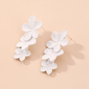 Detail view of elegant triple matte white flower earrings with silver studs and metal base