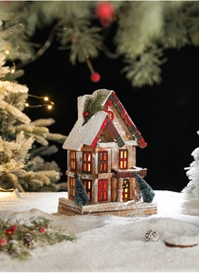 Detail of wooden Christmas house with red-green plaid, snow effects and warm LED glow