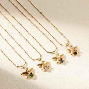 Detail of four gold star necklaces with pearls and colorful gems on a soft background