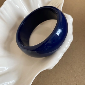 Detail of a deep blue resin wide cuff bracelet with a polished marble-like finish