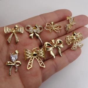 Golden bow pendant necklaces with micro-pave cubic zirconia held in hand on white background