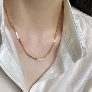 Close-up of a double-layered golden snake bone chain necklace on a silk background
