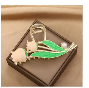 Close-up of tulip hair claw clip with pink petals, green leaves and a faux pearl
