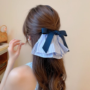 Detail von dunkelblauer Schleife und gestreiftem Haarschmuck am Hinterkopf des Models