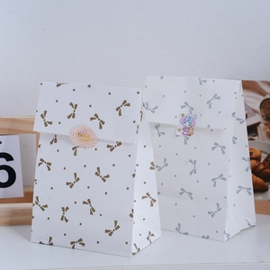 Detailed view of paper gift bags with bow knots and Thank You stickers on background