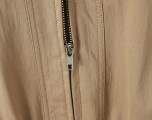 Detail of khaki functional windbreaker showing metal zipper and durable nylon fabric