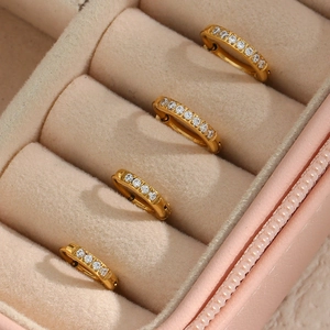 Close-up of four gold-plated titanium steel hoop earrings with zircons in a pink velvet box