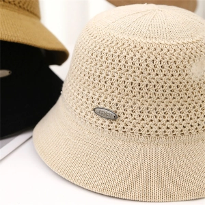 Macro shot of breathable hollow knit bucket hat with elegant oval metal logo detail