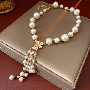 Elegant gold flower pearl tassel necklace displayed on a luxury champagne gift box