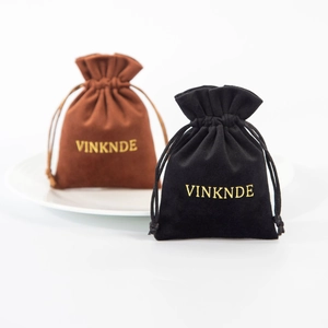 Close-up of black and brown velvet drawstring jewelry pouches with gold stamped logo