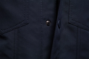 Dettaglio del tessuto twill blu navy con bottoni a pressione in metallo grigio e cuciture