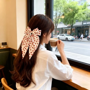 Oversize cream bow hair clip with red strawberry print and long flowing ribbons