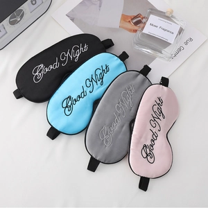 Flat lay of silk sleep masks in black, blue, pink and grey with Good Night embroidery